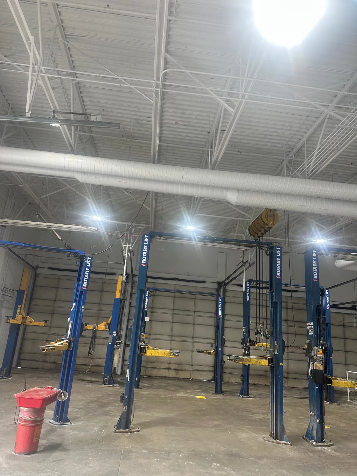 The same service bays after painting: bright white ceiling and trusses above the vehicle lifts