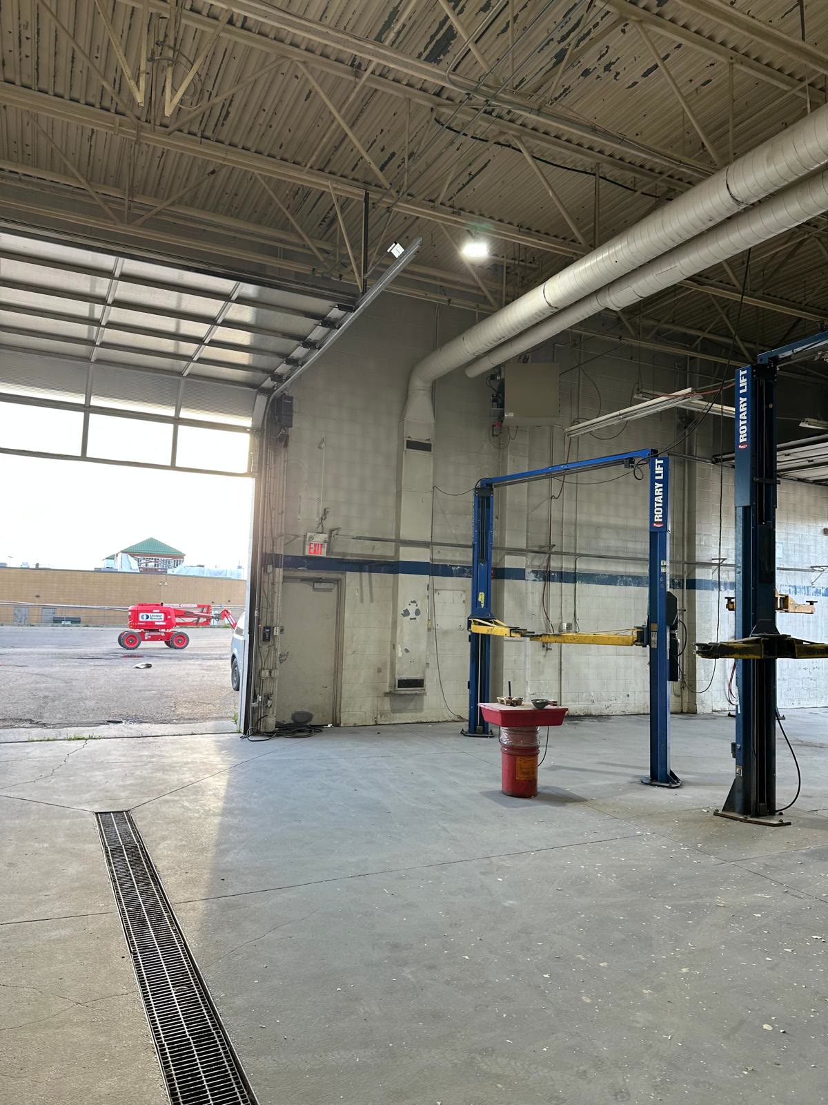 Main shop floor before painting: dingy walls and ceiling beside the overhead door