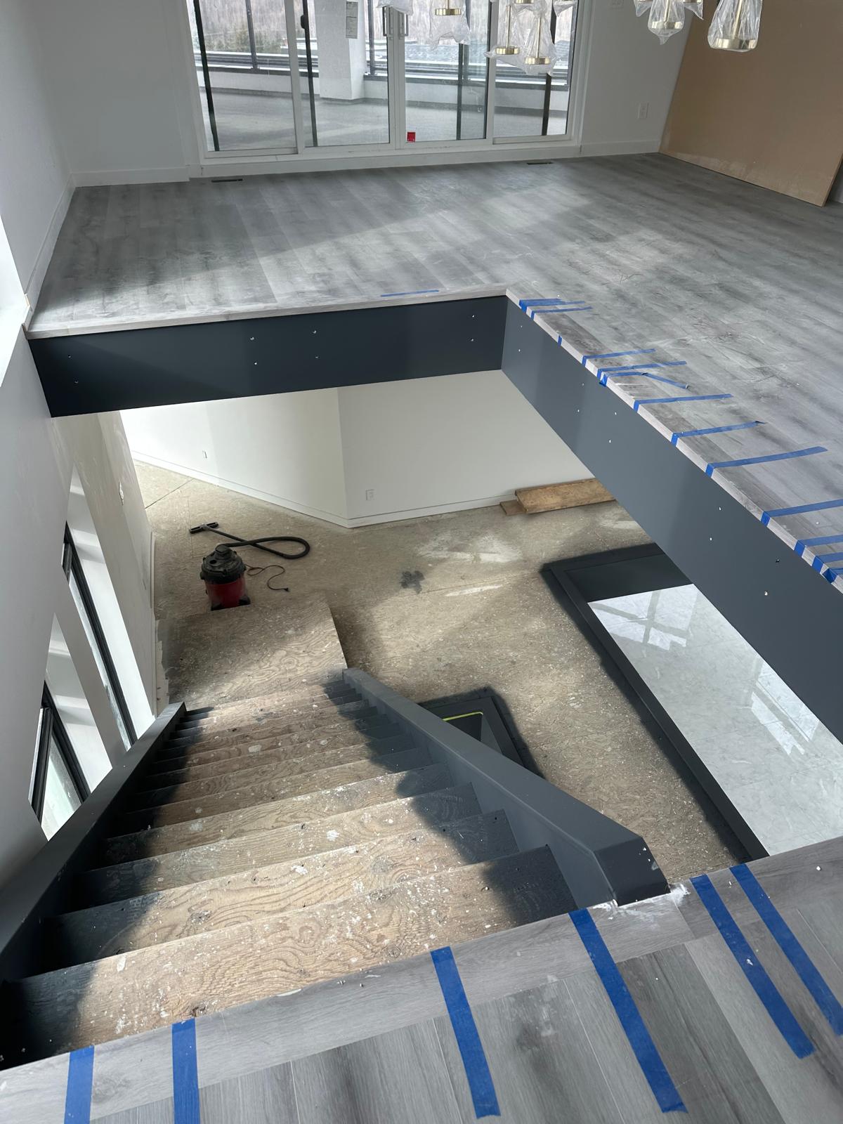 Great room during construction with raw plywood stair treads, taped floors, and bare walls